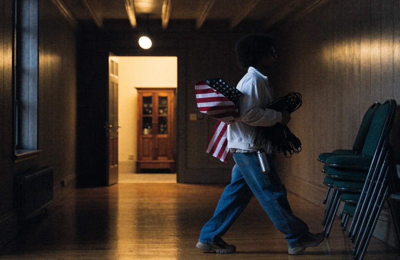 Aide carrying equipment toward the lit doorway of an Ohio campaign hall before a Senate event